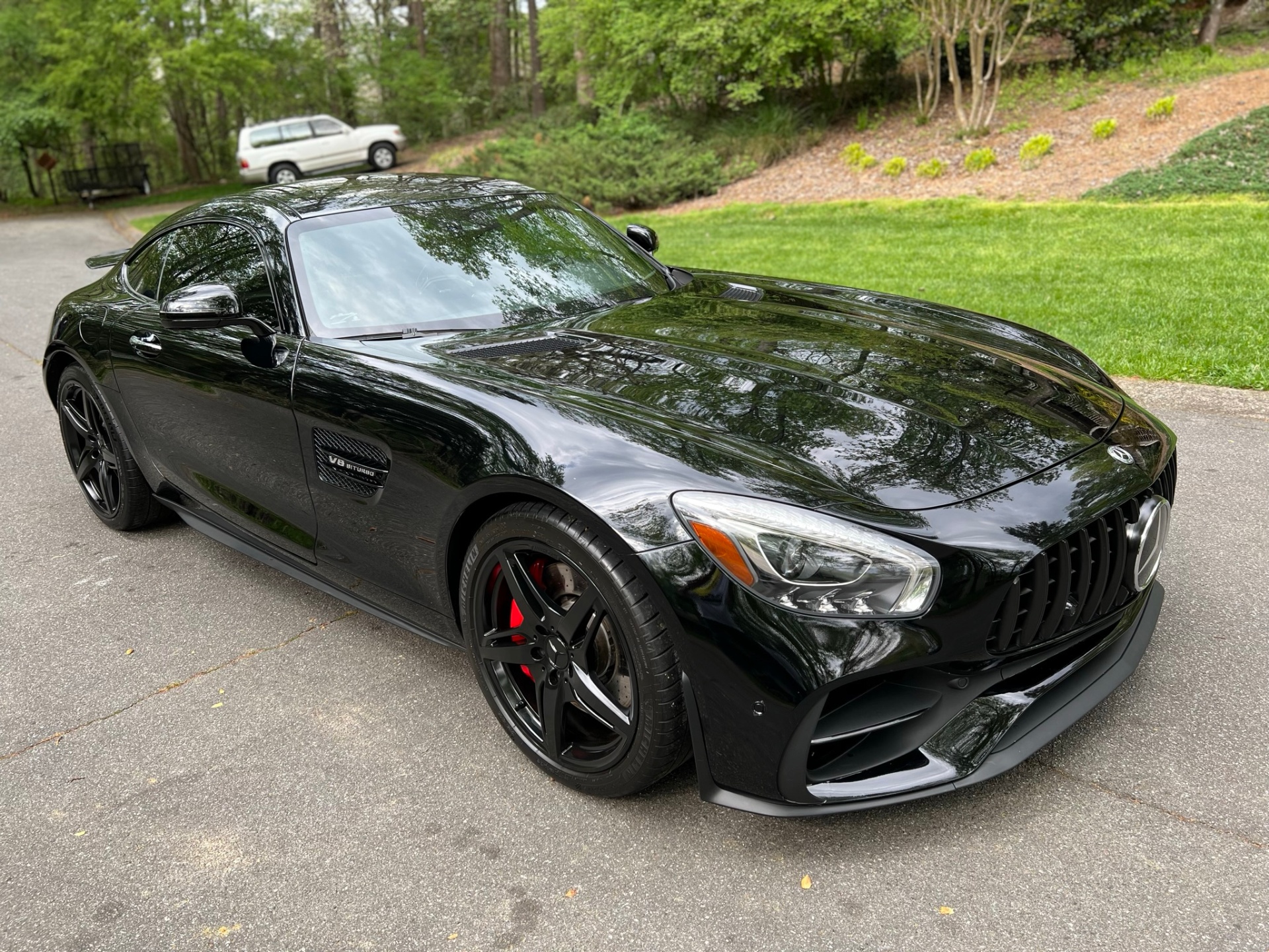 Black Mercedes-AMG GT coupe with glossy reflections and red brake calipers.