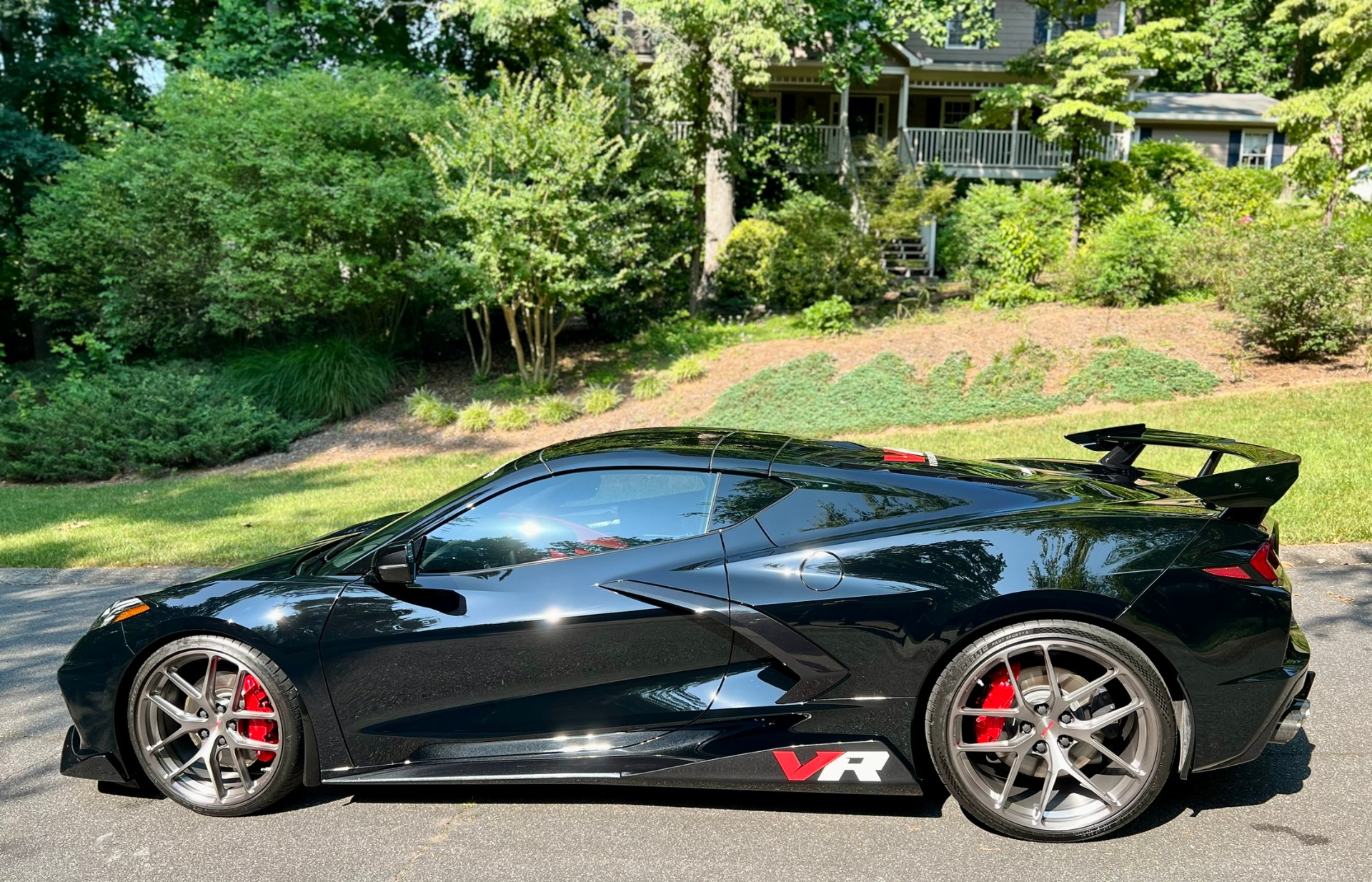 Black Corvette C8 side profile with red brake calipers and large rear wing.